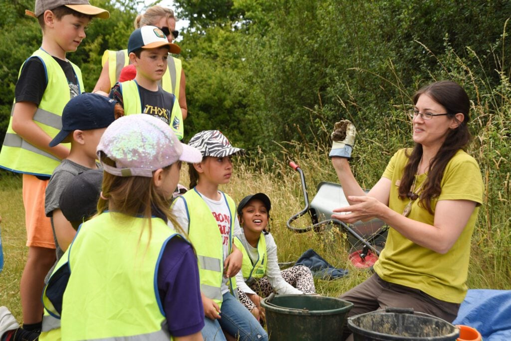 Pupils in meadow with Sussex Wildlife Trust staff member
