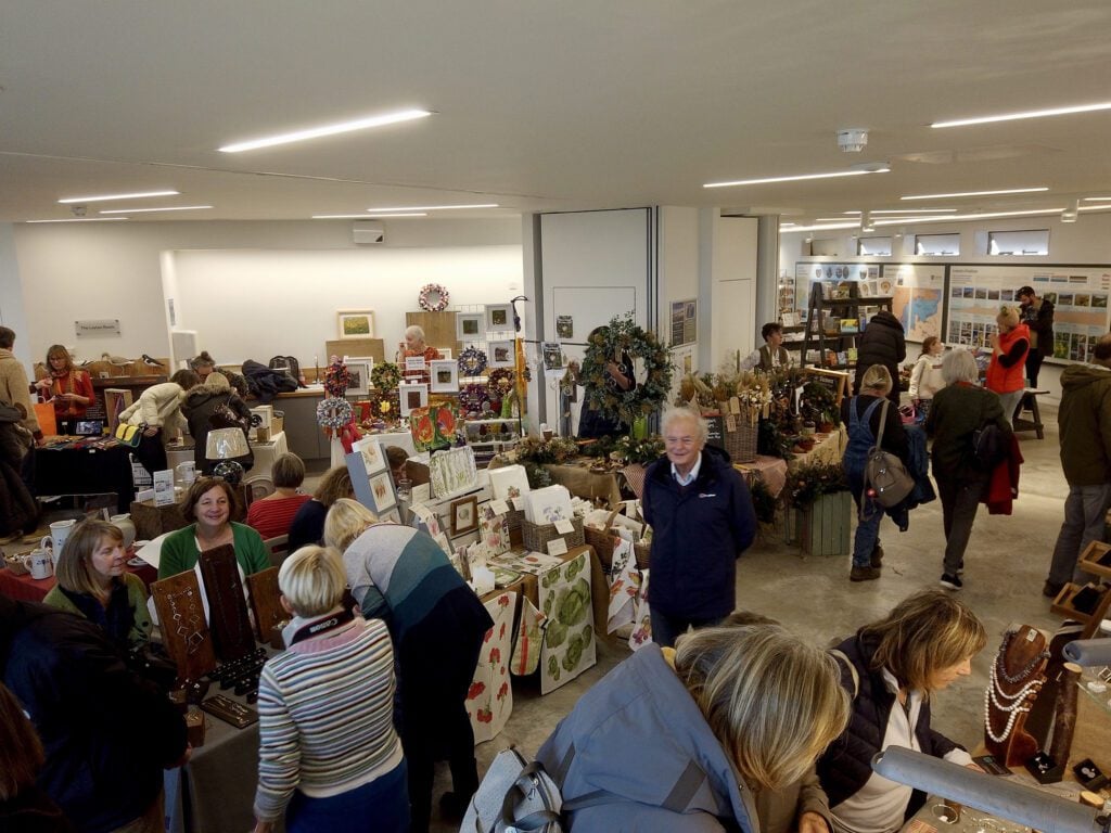 Indoor market stalls with crafts and Christmas gifts with people browsing 