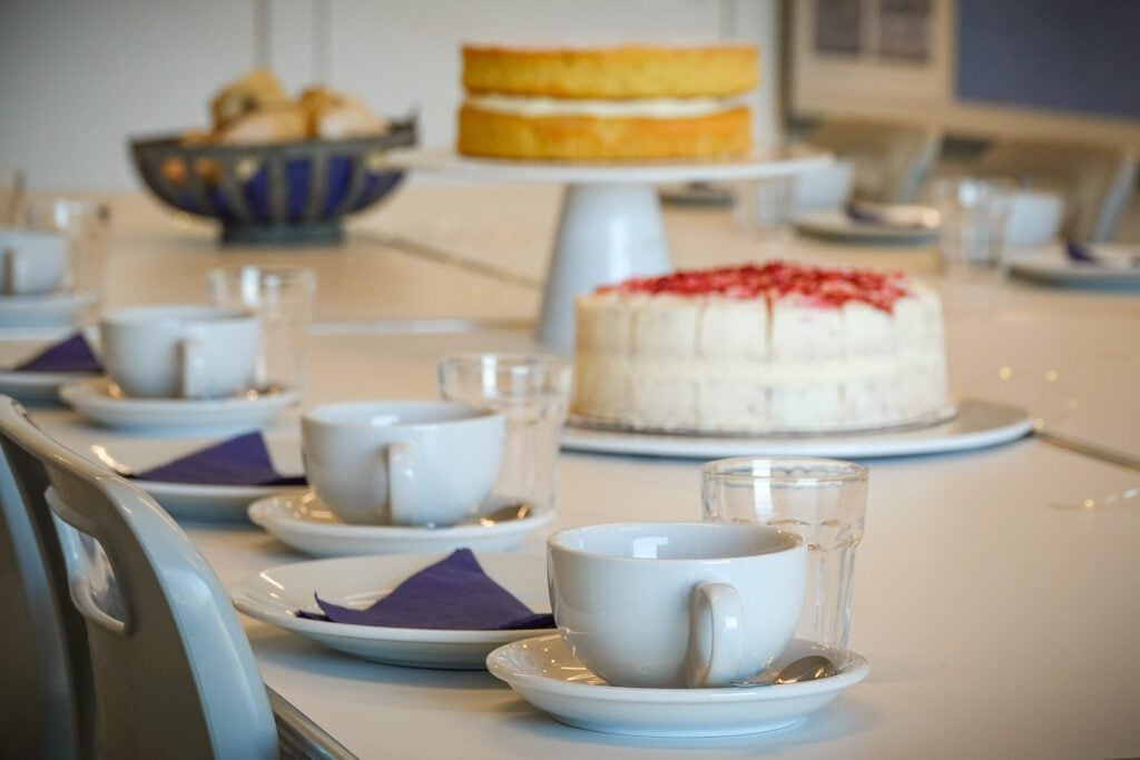 Cakes, cups and plates laid out on white table