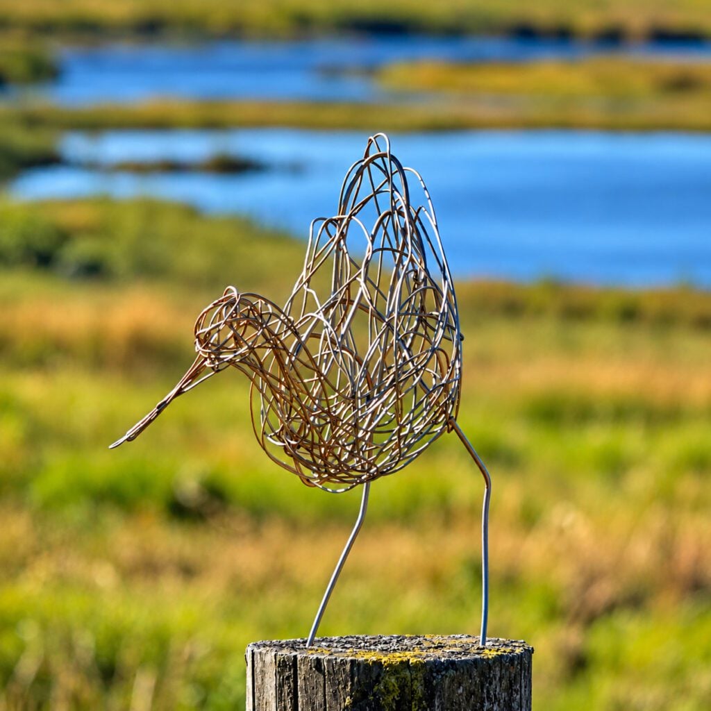 Avocet made of wire perched on fence post